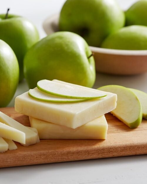 Wooden chopping board with apples and cheese