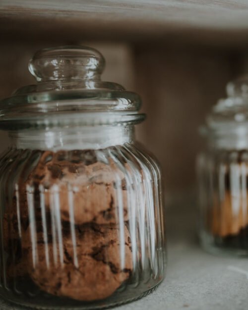 Food storage jars arranged on wooden kitchen shelves